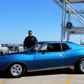 Man smiling behind blue antique car